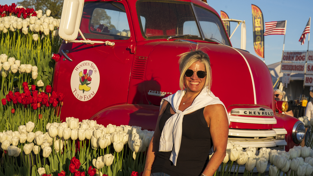Guest at Tulip Festival with Red Truck Woman smiling next to red vintage truck surrounded by tulips